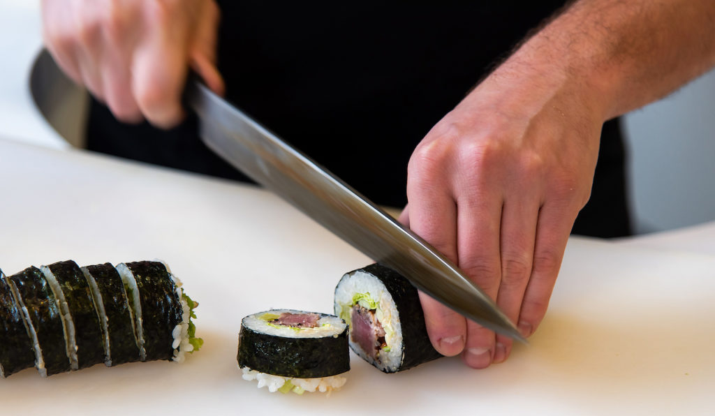 Chef cutting sushi rolls with sharp knife