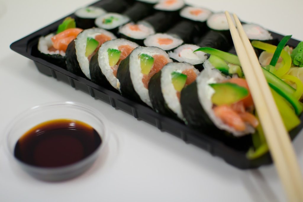 Sushi rolls made by a sushi robot with soy sauce on the side